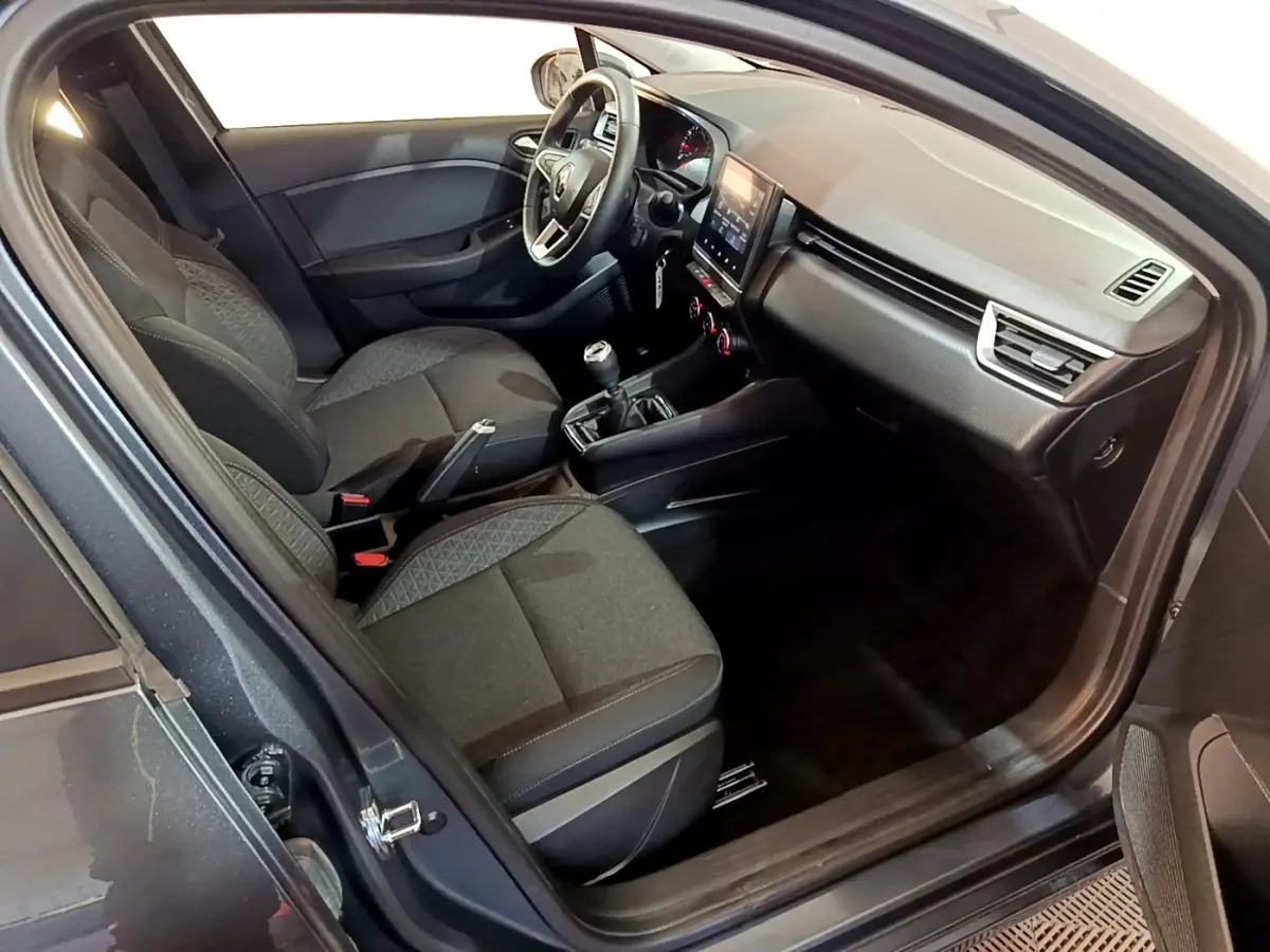 Vue intérieure côté conducteur de la Renault Clio Business TCe 90 2022, sièges tissu gris foncé et tableau de bord moderne.