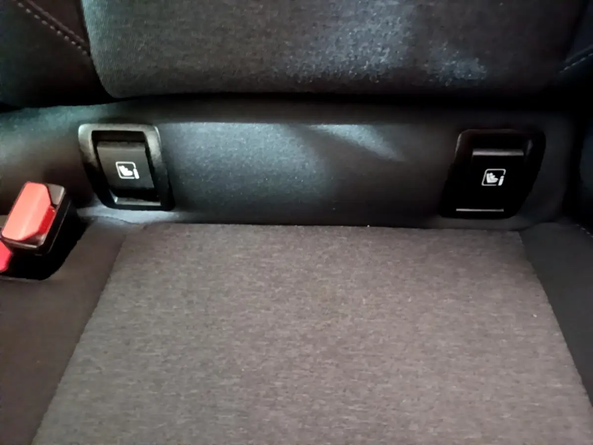 Gros plan sur les commandes de rabattement des sièges arrière et la ceinture de sécurité dans une Renault Clio Business gris foncé.