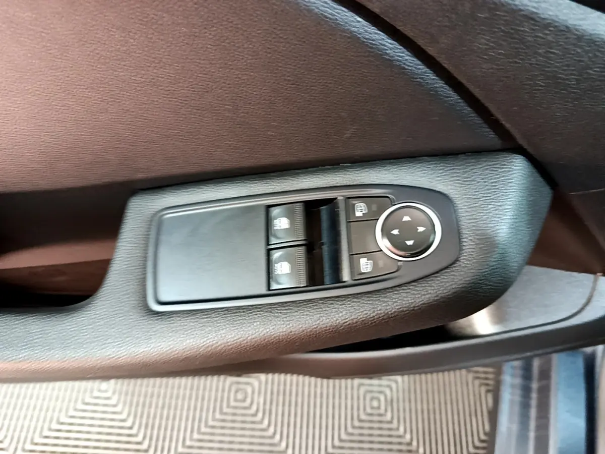 Gros plan sur les commandes de réglage des rétroviseurs chauffants côté conducteur d'une Renault Clio Business gris foncé 2022.