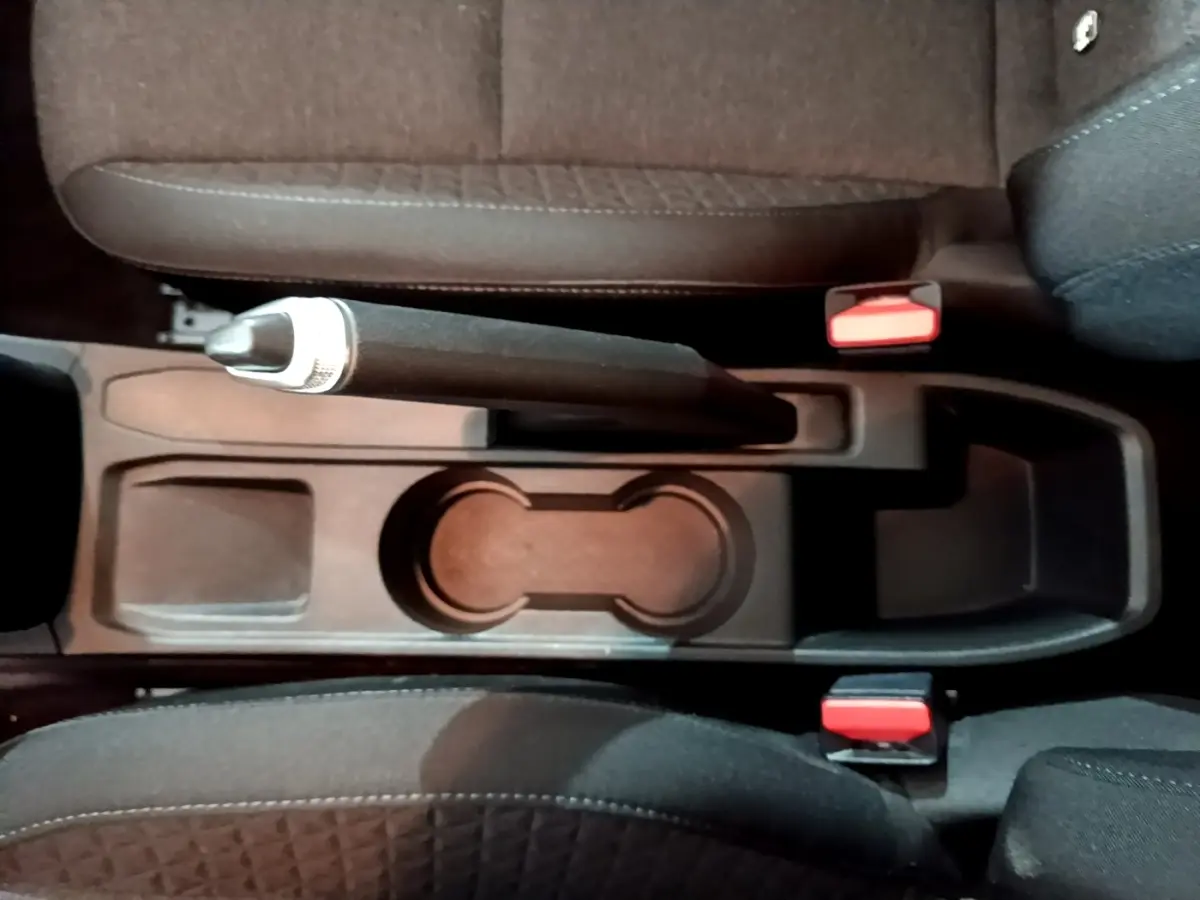 Vue plongeante sur la console centrale noire avec frein à main manuel et sièges tissu gris foncé d'une Renault Clio Business 2022.