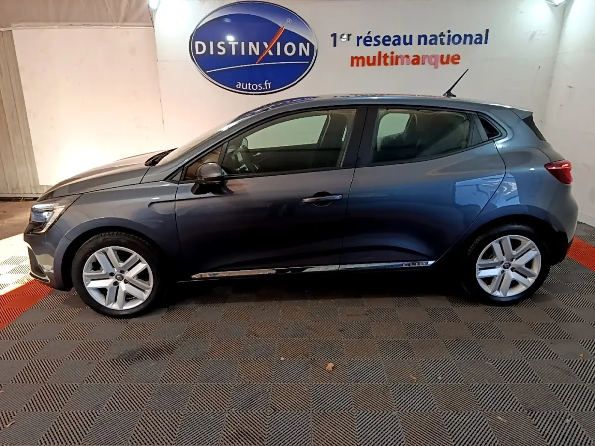 Profil côté gauche d'une Renault Clio Business TCe 90 gris foncé 2022, avec jantes alliage et logo Distinxion en arrière-plan.