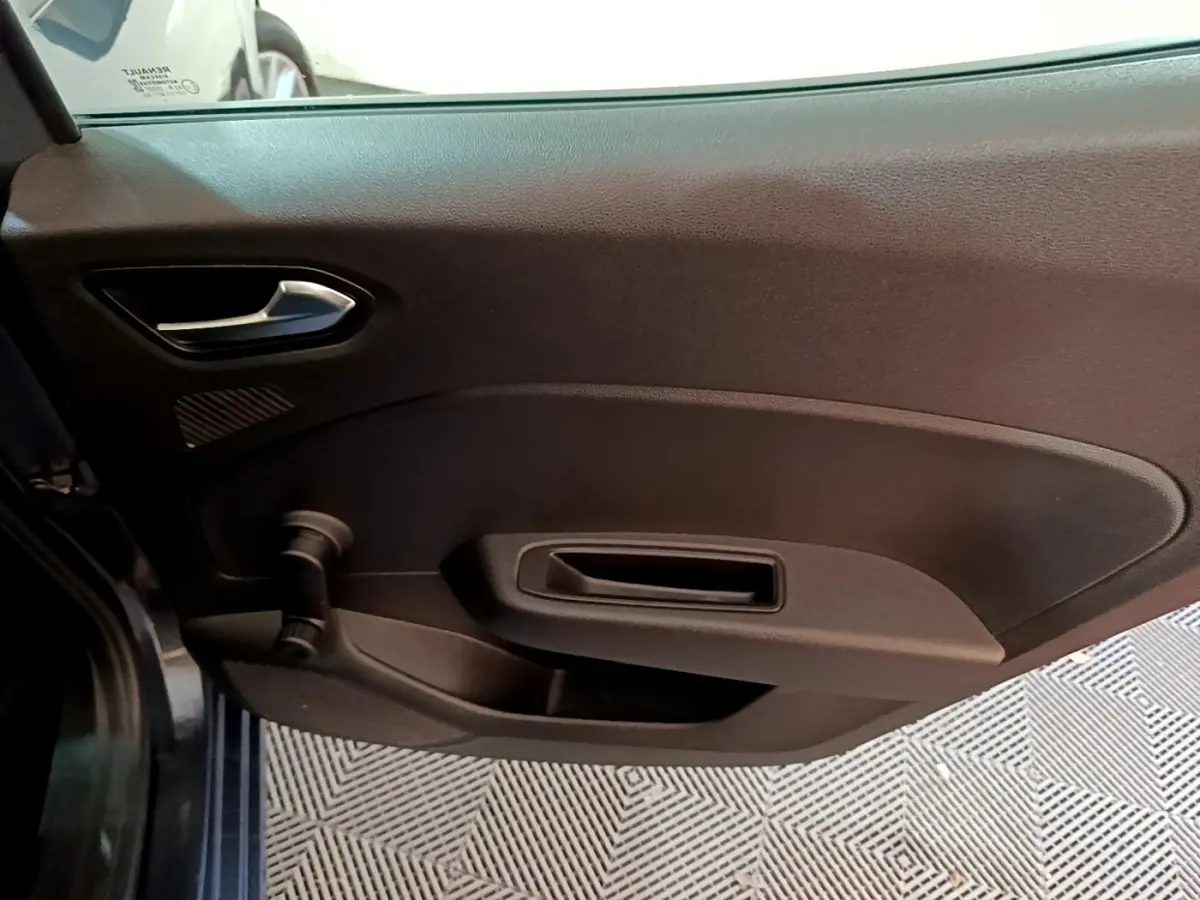 Vue intérieure du panneau de porte côté gauche d'une Renault Clio Business TCe 90 gris foncé, avec poignée et manivelle de vitre.