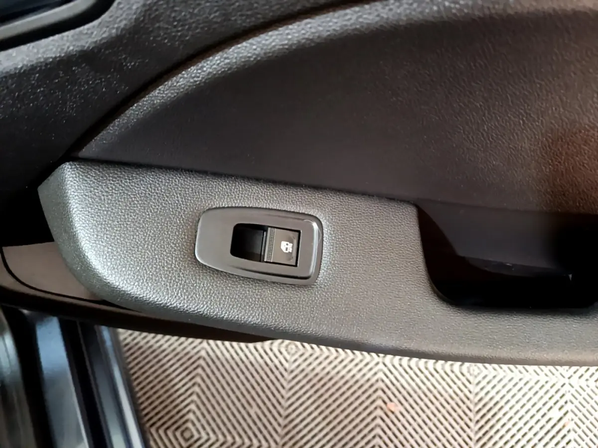 Bouton de commande de vitre électrique sur la portière côté gauche d'une Renault Clio gris foncé 2022.