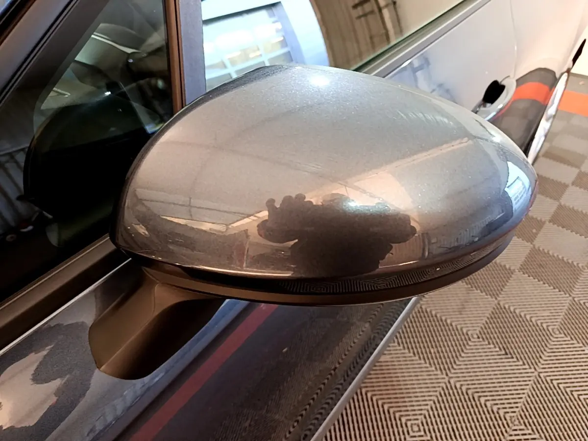 Rétroviseur côté gauche gris foncé de la Renault Clio Business TCe 90 vue en gros plan avec reflet intérieur.