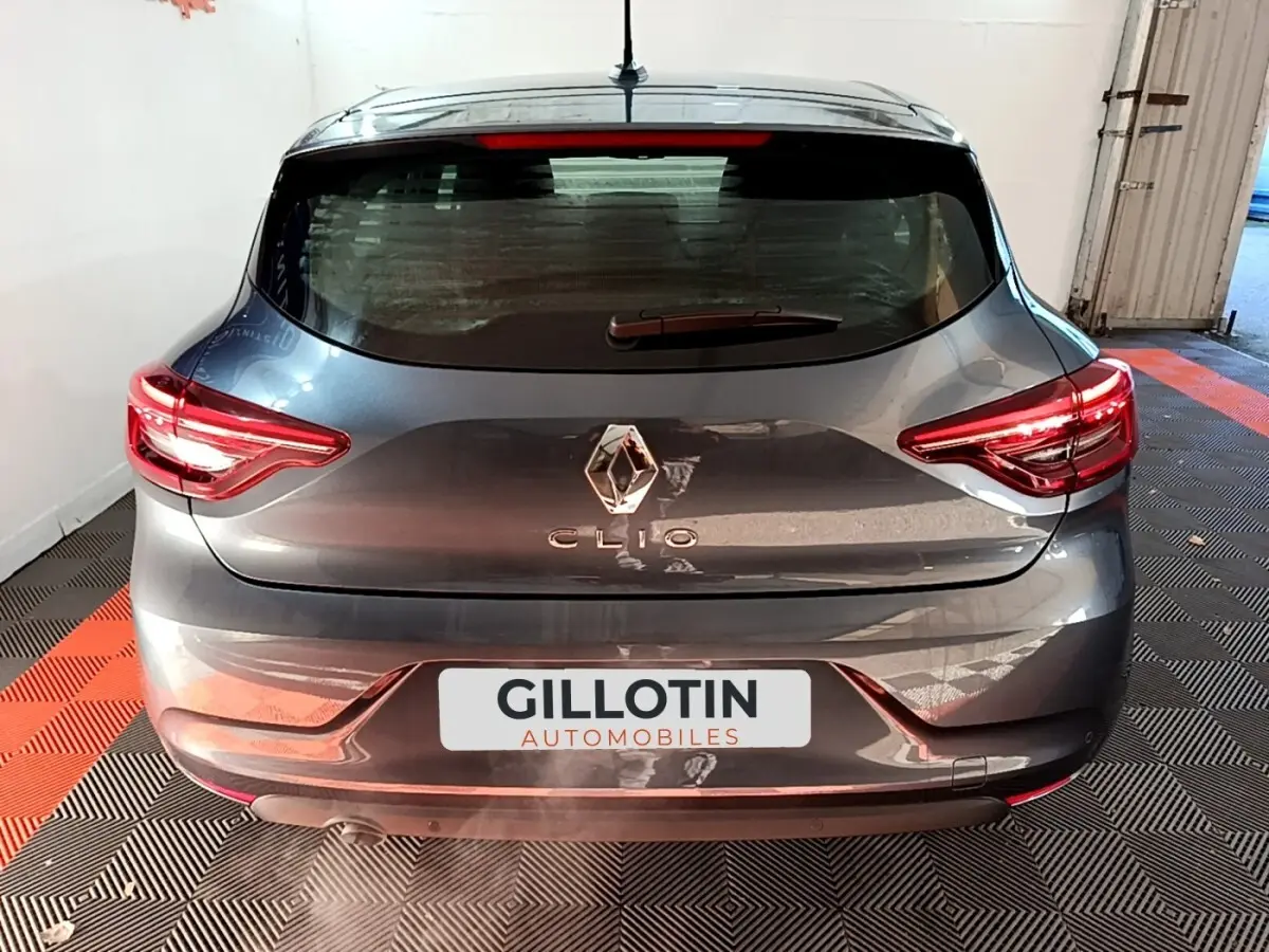 Vue arrière d'une Renault Clio gris foncé avec feux LED et logo centré sur un sol à damier noir et orange.