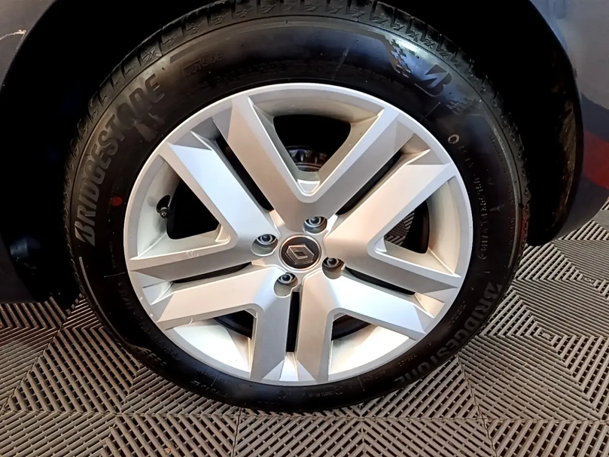 Gros plan sur la jante alliage argentée avec logo Renault au centre, roue avant d'une Clio Business gris foncé.