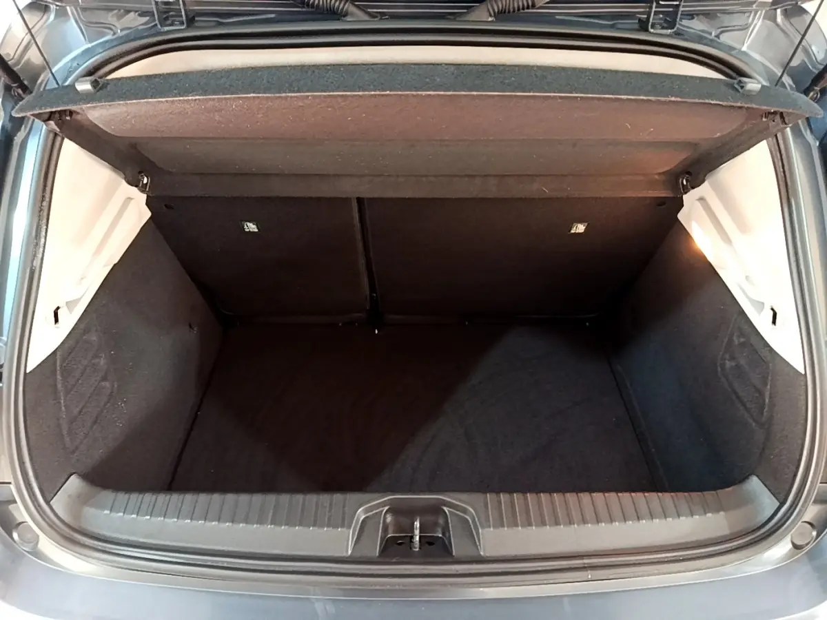 Coffre ouvert vu de l'arrière d'une Renault Clio Business TCe 90 gris foncé, montrant l'espace de chargement vide.