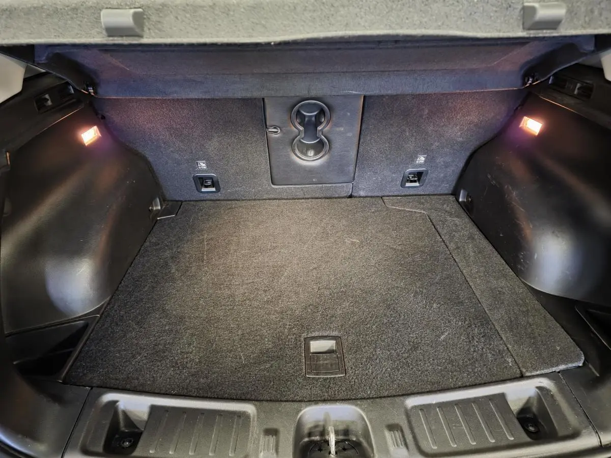 Coffre spacieux du Jeep Compass Trailhawk 2024 noir, avec éclairage intérieur et tapis de coffre gris.