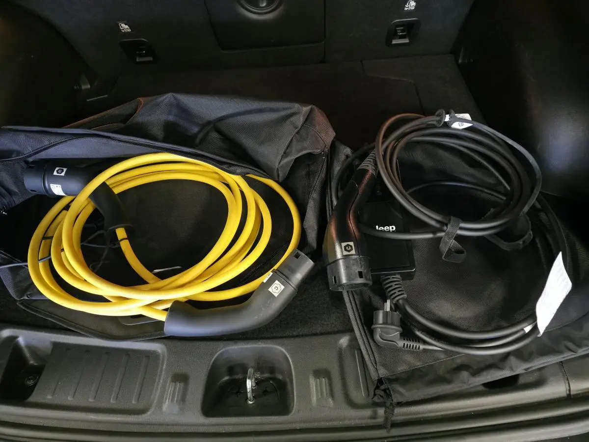Vue rapprochée du coffre du Jeep Compass Trailhawk 2024 montrant deux câbles de recharge, jaune et noir.