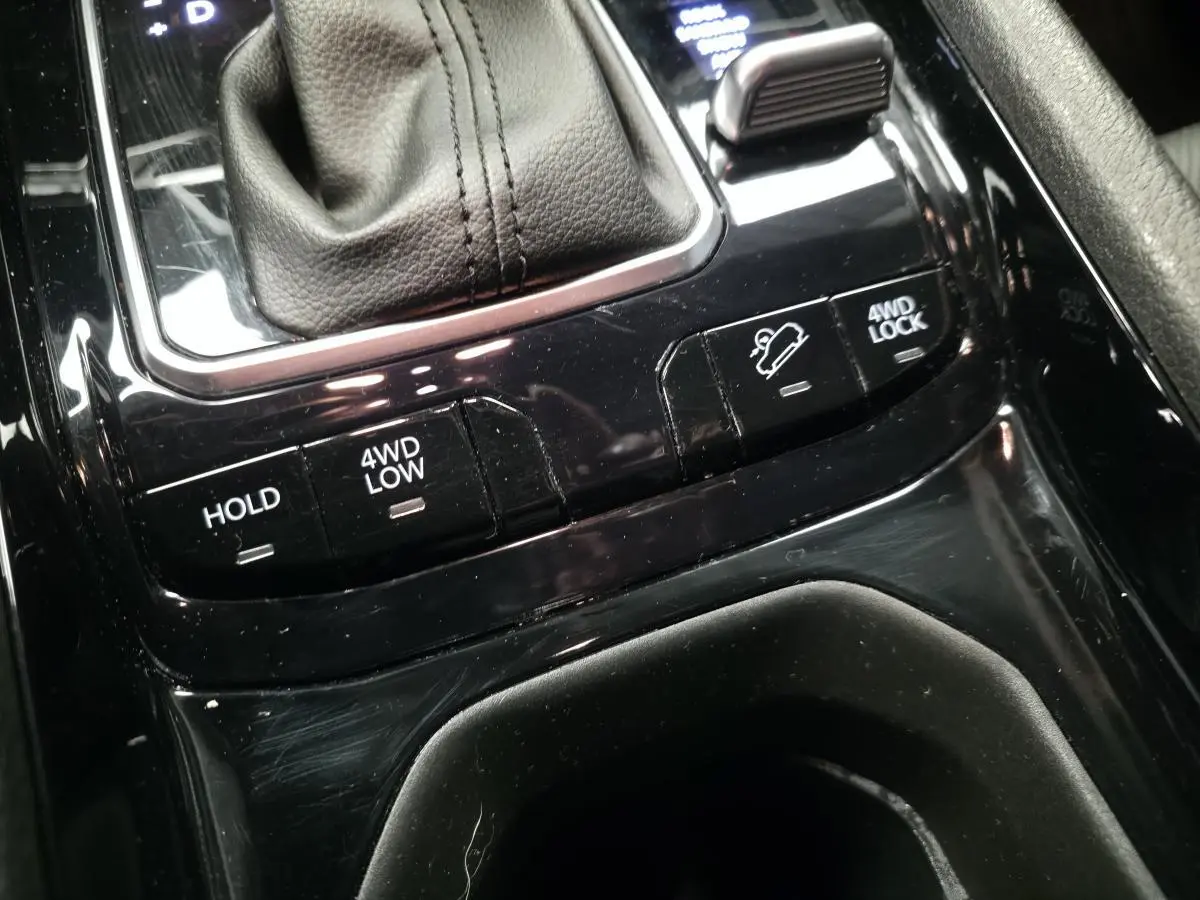 Gros plan sur la console centrale noire du Jeep Compass 2024 avec commandes 4WD et frein de stationnement automatique.