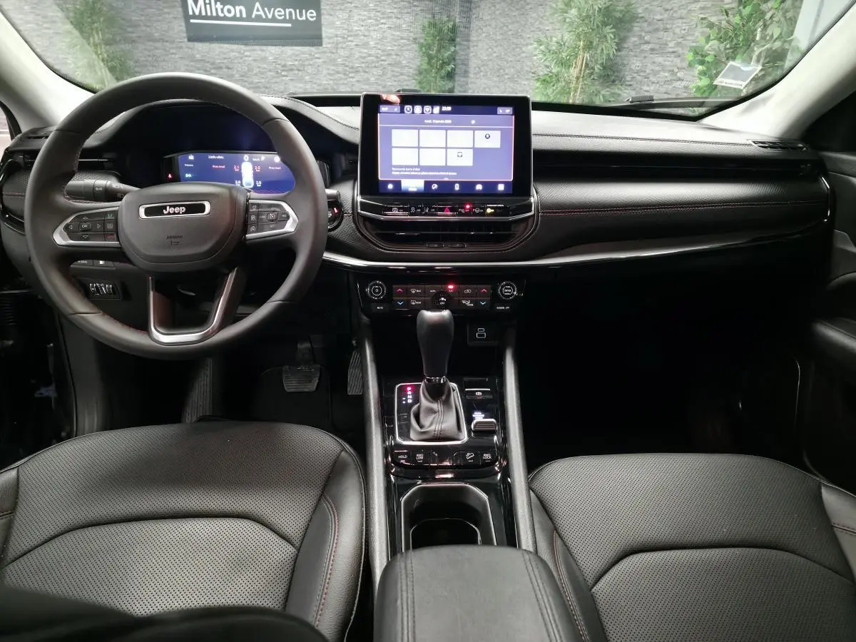 Intérieur noir du Jeep Compass 2024 vu de face, avec tableau de bord numérique et écran tactile central.