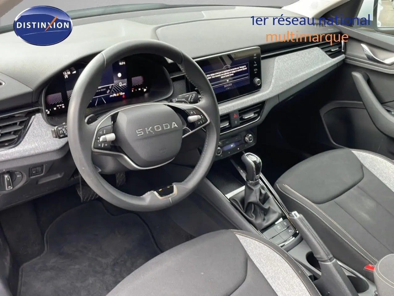 Vue intérieure côté conducteur du Skoda Kamiq 2025 avec volant multifonction, tableau de bord numérique et sellerie tissu noir et gris.