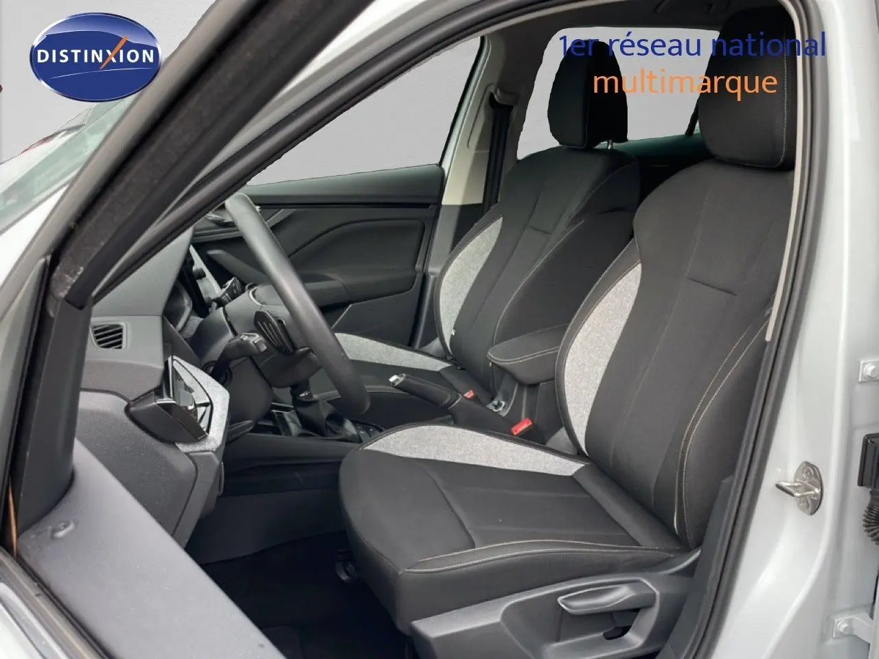 Vue intérieure côté conducteur du Skoda Kamiq blanc glacier 2025, sièges tissu noir et gris avec volant multifonction.