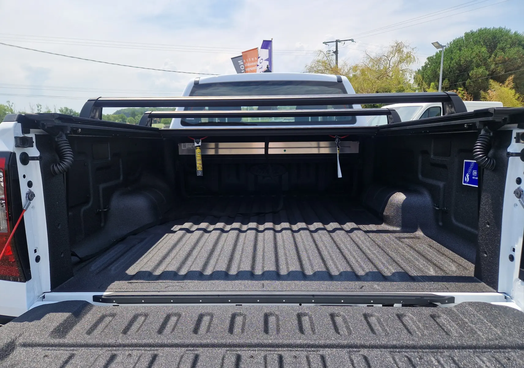 Vue arrière du plateau blanc du Ford Ranger Super Cabine avec rideau rigide coulissant et protection renforcée.