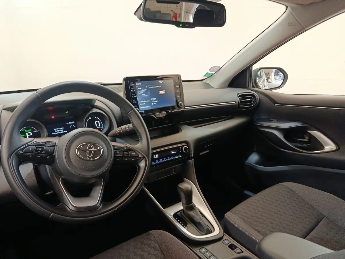 Vue intérieure côté conducteur de la Toyota Yaris Hybride 116h Design 2023, tableau de bord et écran tactile central visibles.