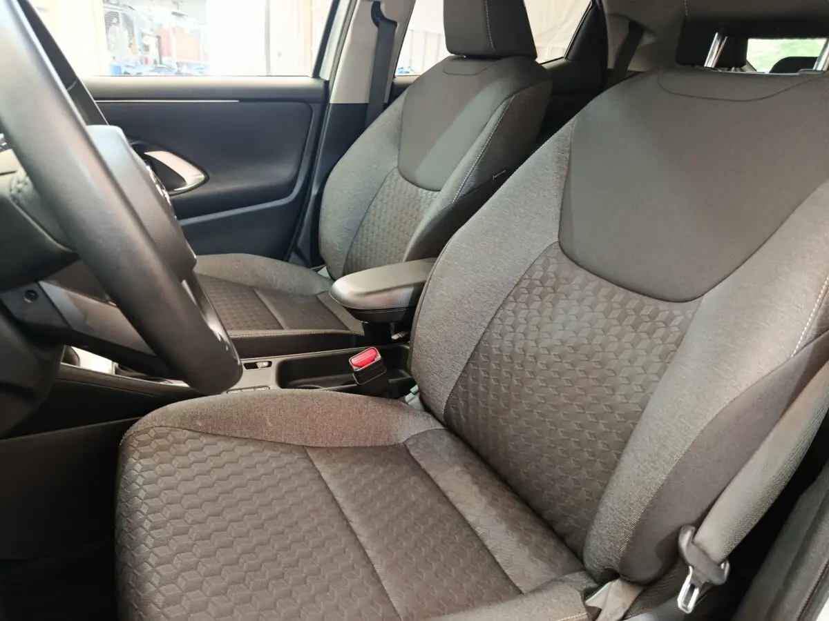 Vue intérieure rapprochée sur les sièges avant gris de la Toyota Yaris Hybride 116h Design 2023, avec volant partiellement visible.