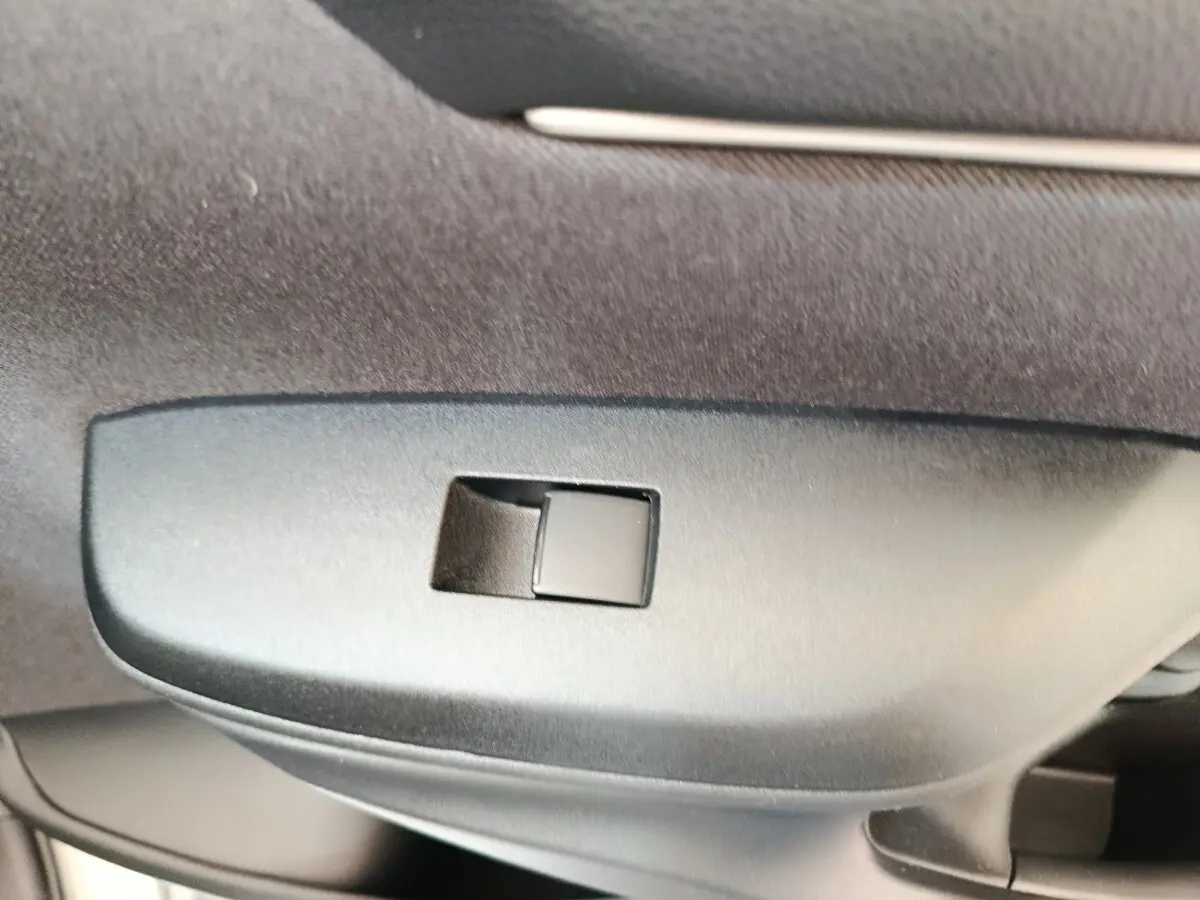 Détail du bouton de verrouillage centralisé sur la porte intérieure d'une Toyota Yaris hybride gris clair.