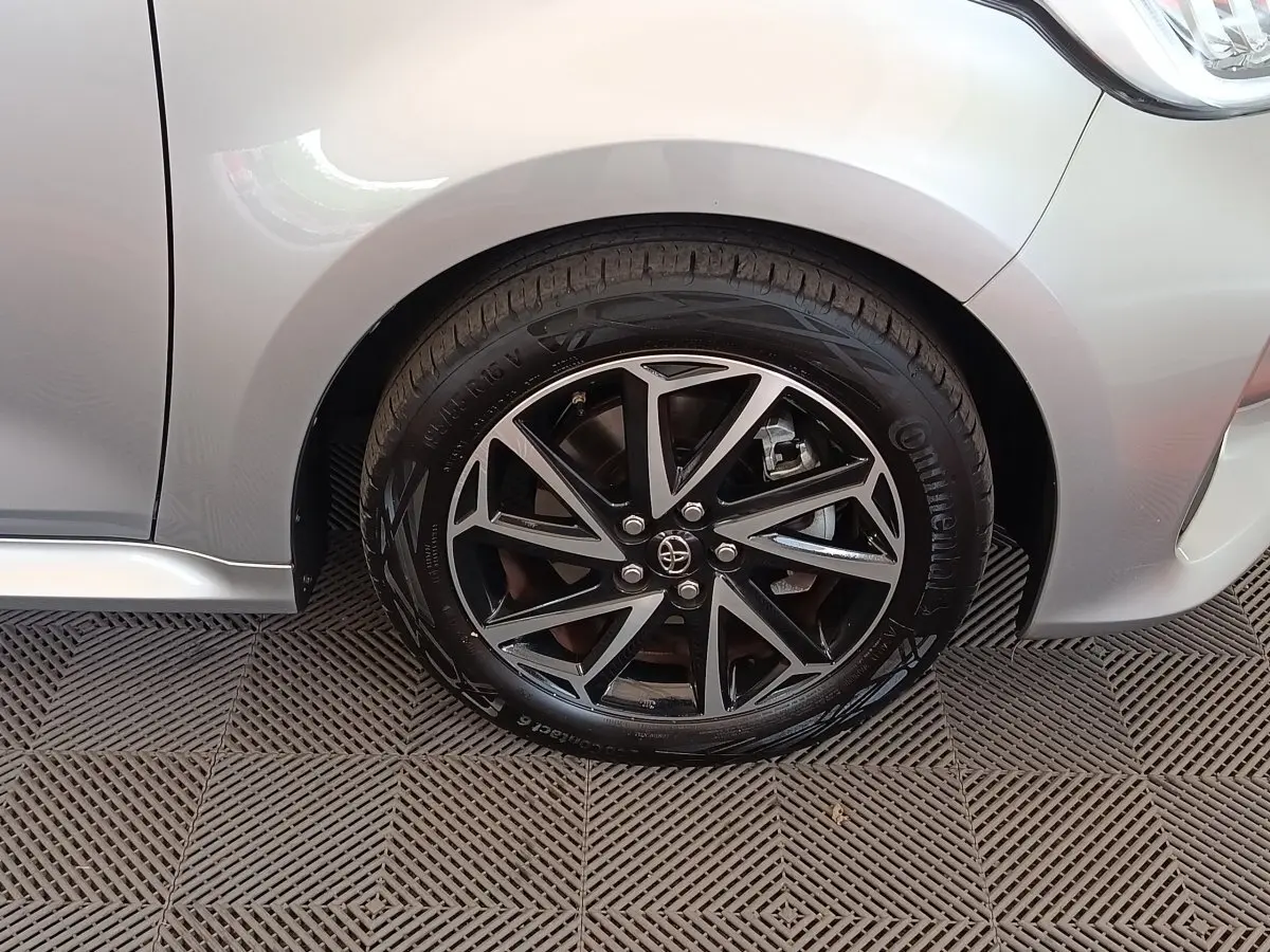 Gros plan sur la roue avant gauche de la Toyota Yaris hybride gris clair, avec jante alliage noire et argentée.