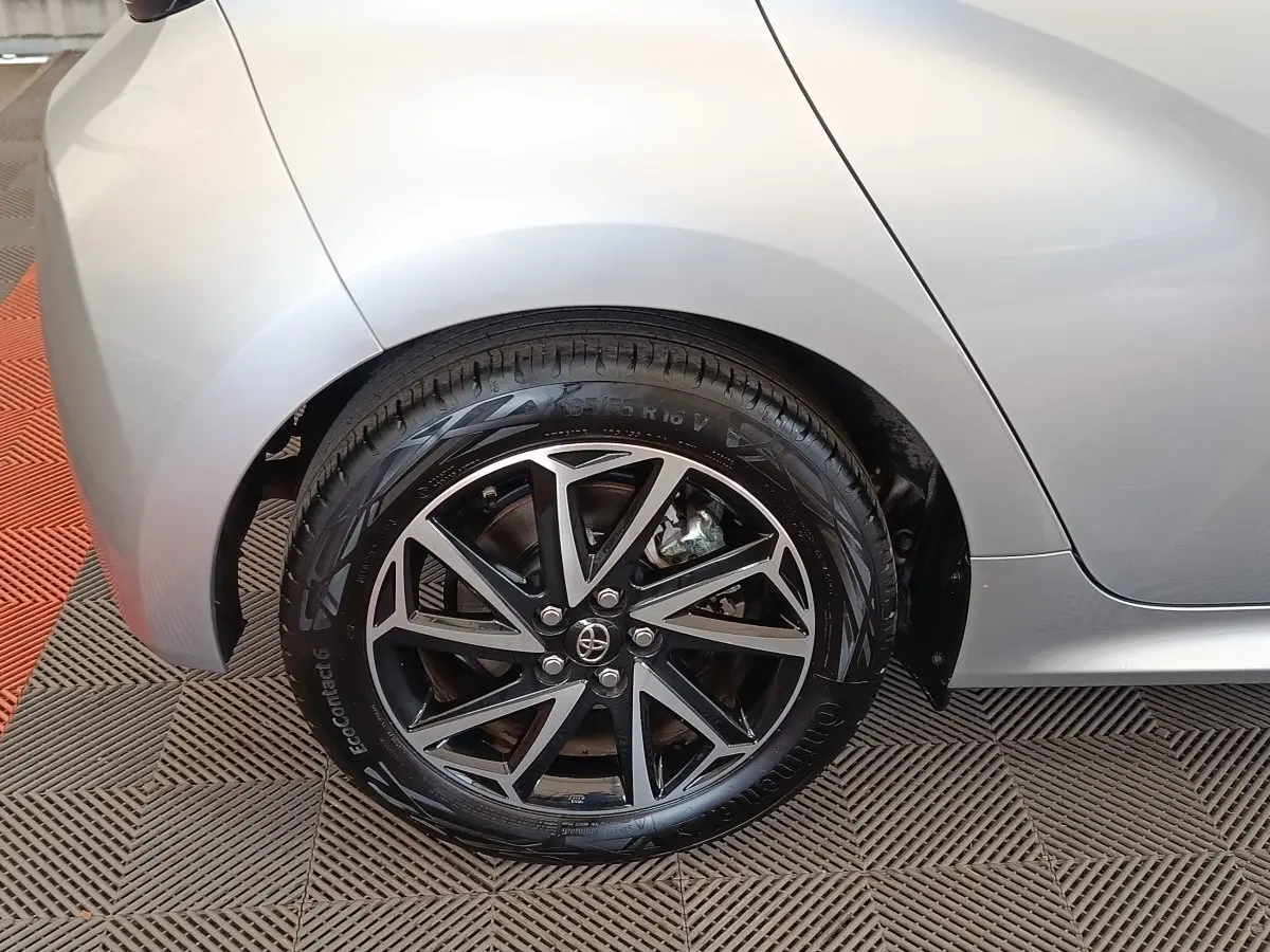 Gros plan sur la roue arrière droite de la Toyota Yaris hybride gris clair, avec jante alliage noire et argentée.