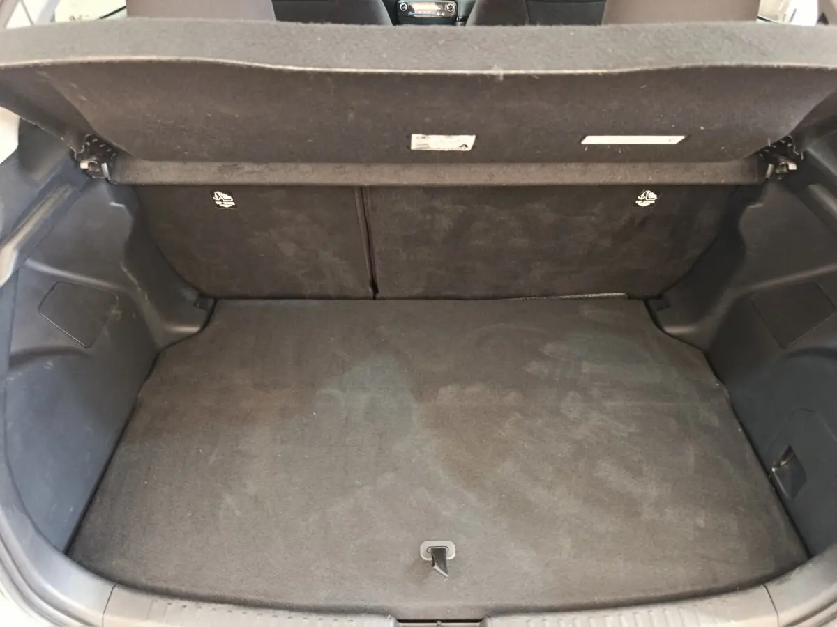 Coffre ouvert de la Toyota Yaris Hybride 116h Design gris clair, montrant un espace de chargement propre et vide.