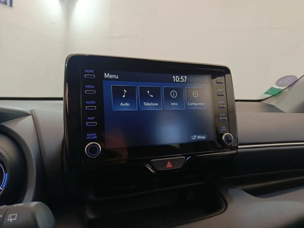 Écran tactile central allumé du tableau de bord d’une Toyota Yaris Hybride gris clair, vue intérieure frontale.