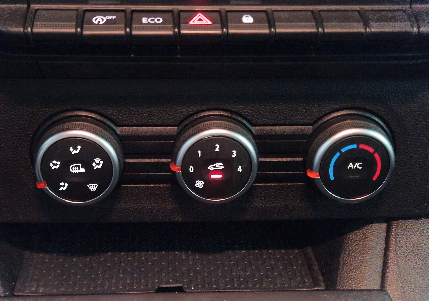 Gros plan sur les commandes de climatisation du Renault Kangoo blanc 2023, avec réglages manuels et bouton A/C visible.