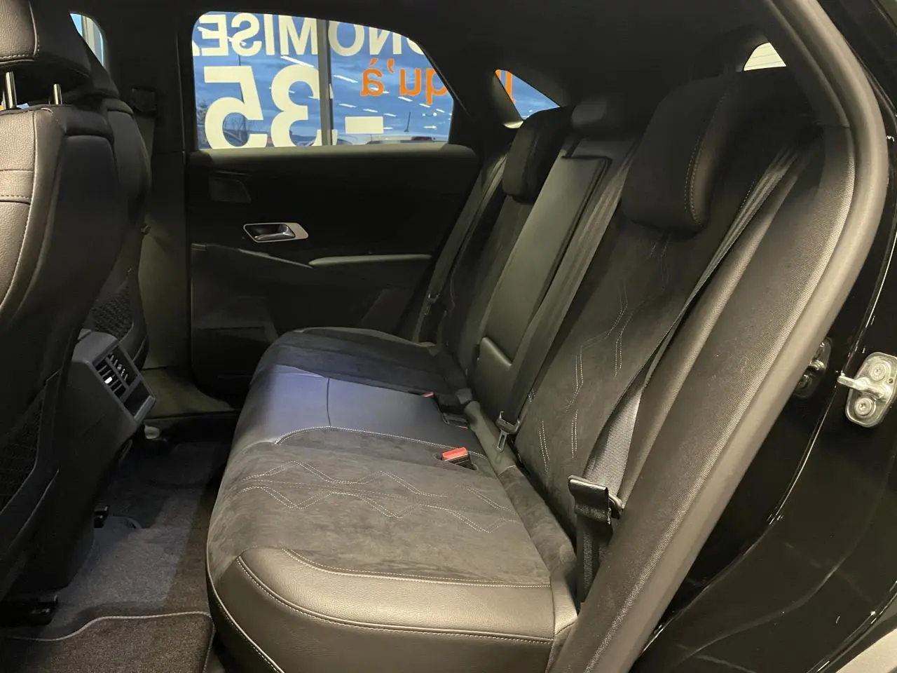 Vue latérale droite de la banquette arrière en Alcantara noir profond du DS7 Crossback avec ceintures de sécurité visibles.
