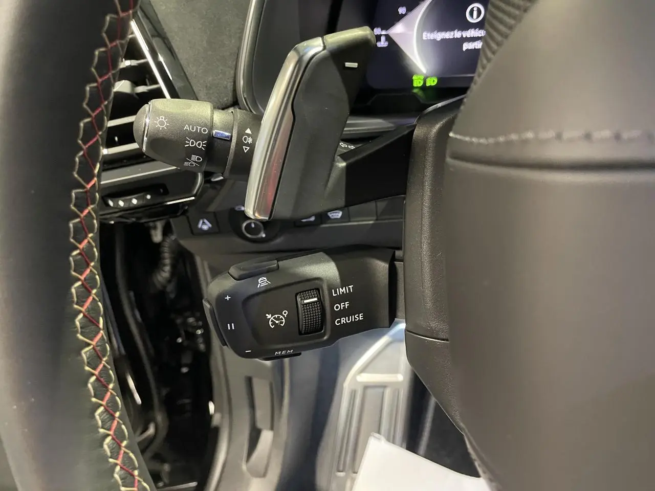 Gros plan sur la commande de régulateur de vitesse au volant cuir noir avec surpiqûres rouges du DS7 Crossback noir métallisé.
