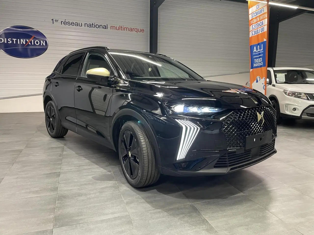 DS7 Crossback noir métallisé en 3/4 avant droit, avec calandre DS Wings et feux LED verticaux allumés.