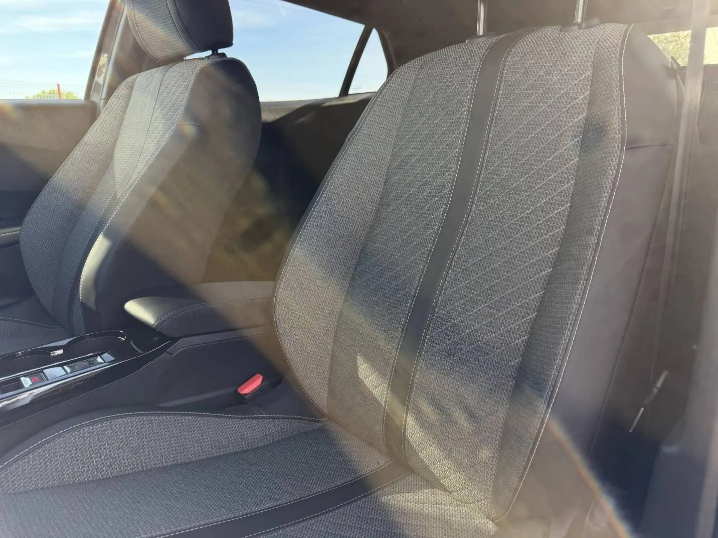 Gros plan sur les sièges avant en tissu gris Casual Lomsa embossé du Peugeot e-2008 2025, lumière naturelle traversante.