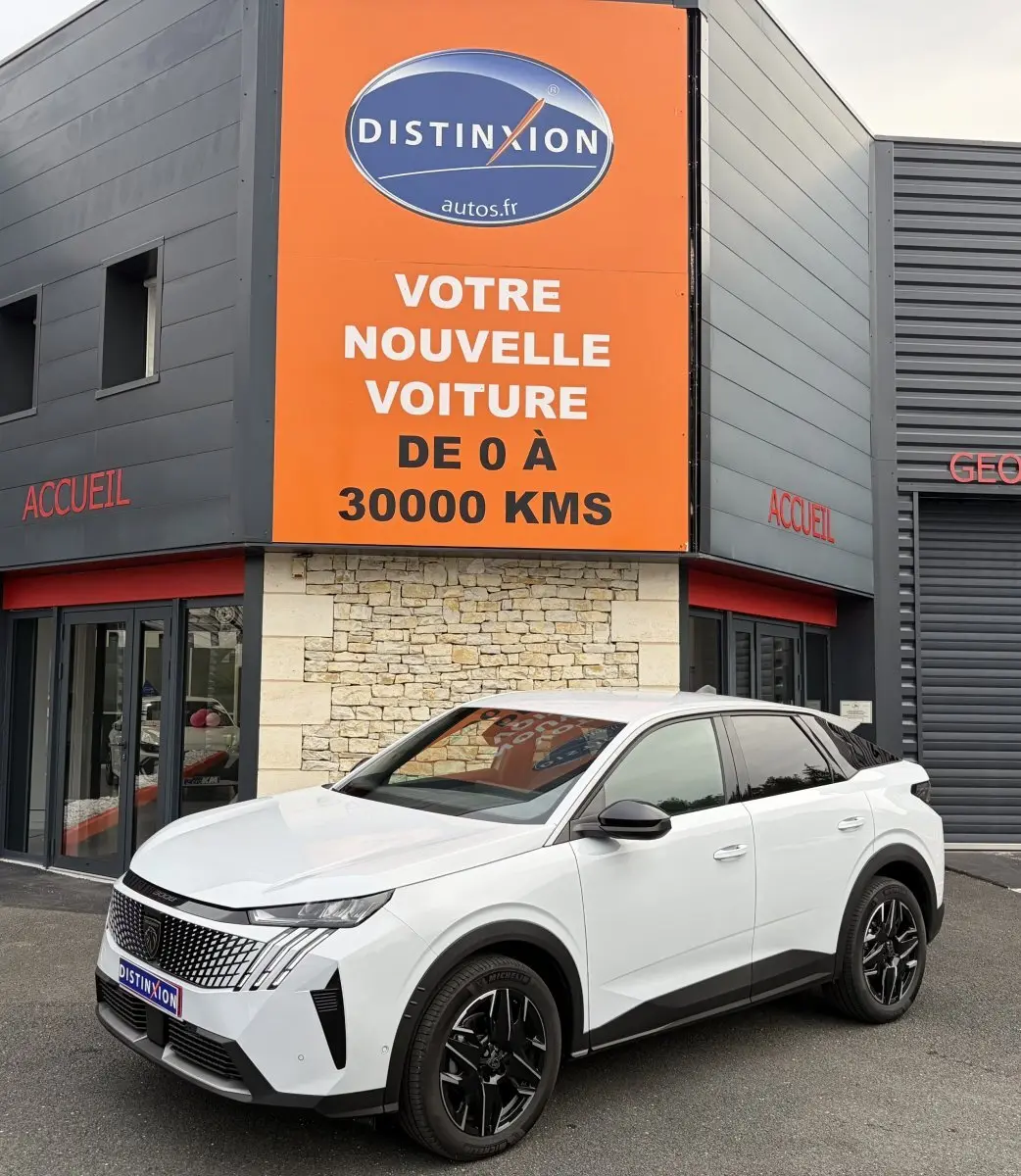 Peugeot 3008 blanc en 3/4 avant droit, avec jantes noires et calandre distinctive, devant un bâtiment commercial.