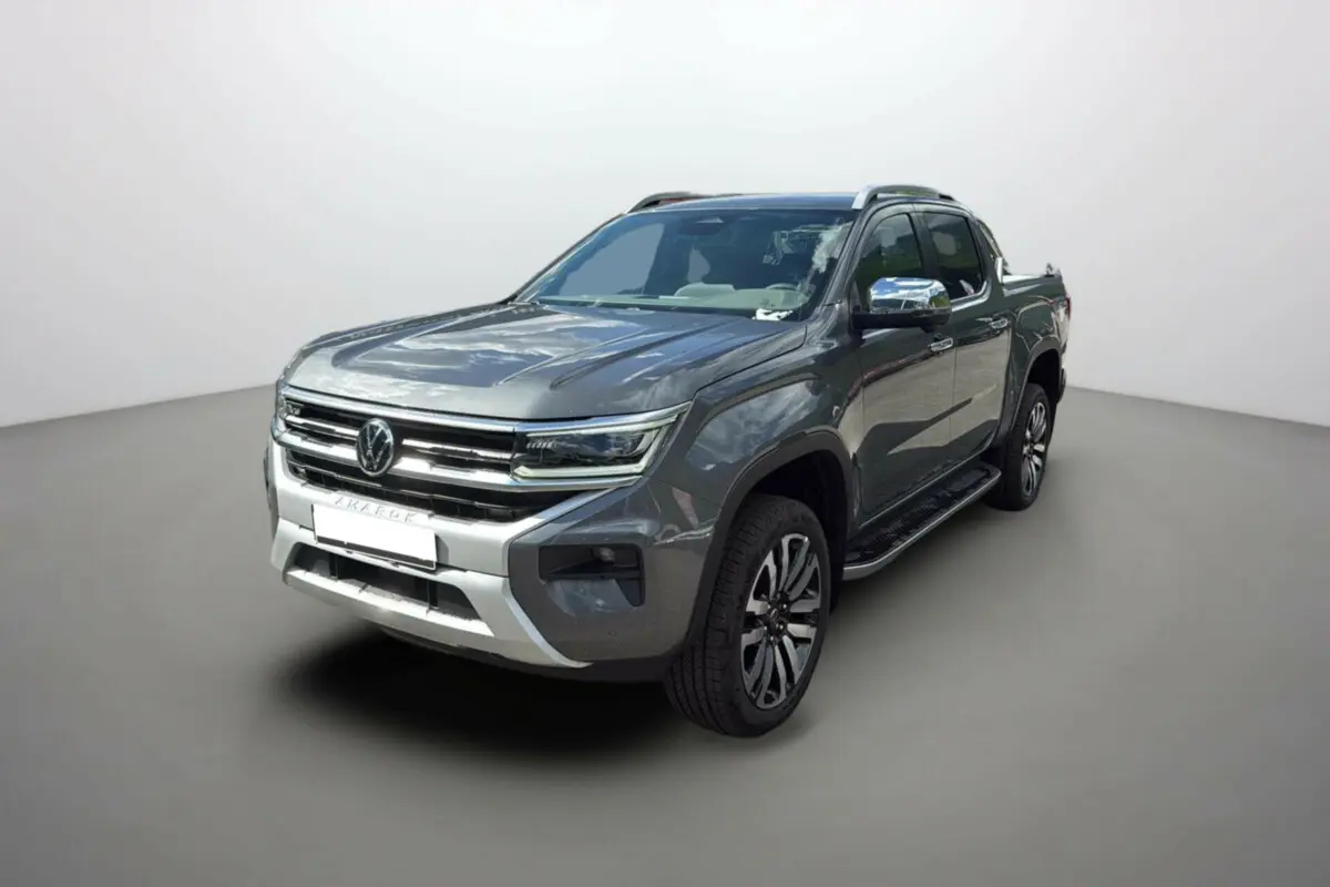 Vue 3/4 avant droite d'un Volkswagen Amarok Simple Cabine 2025 gris foncé avec calandre chromée et jantes alliage.