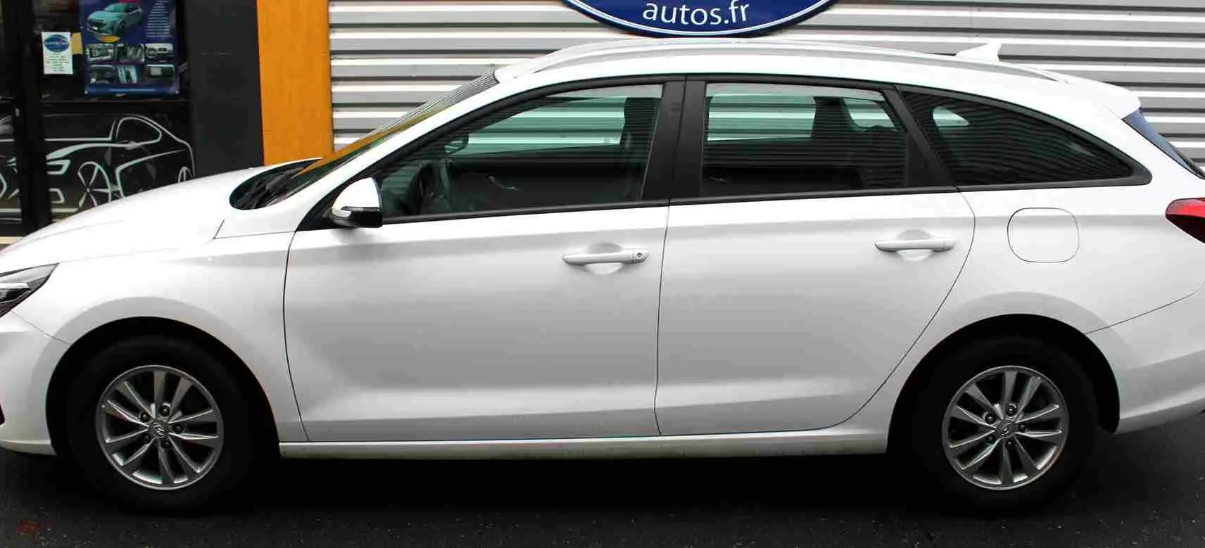 Profil côté gauche d'une Hyundai i30 SW 2022 blanche polaire, break compact avec jantes alliage et vitres teintées.