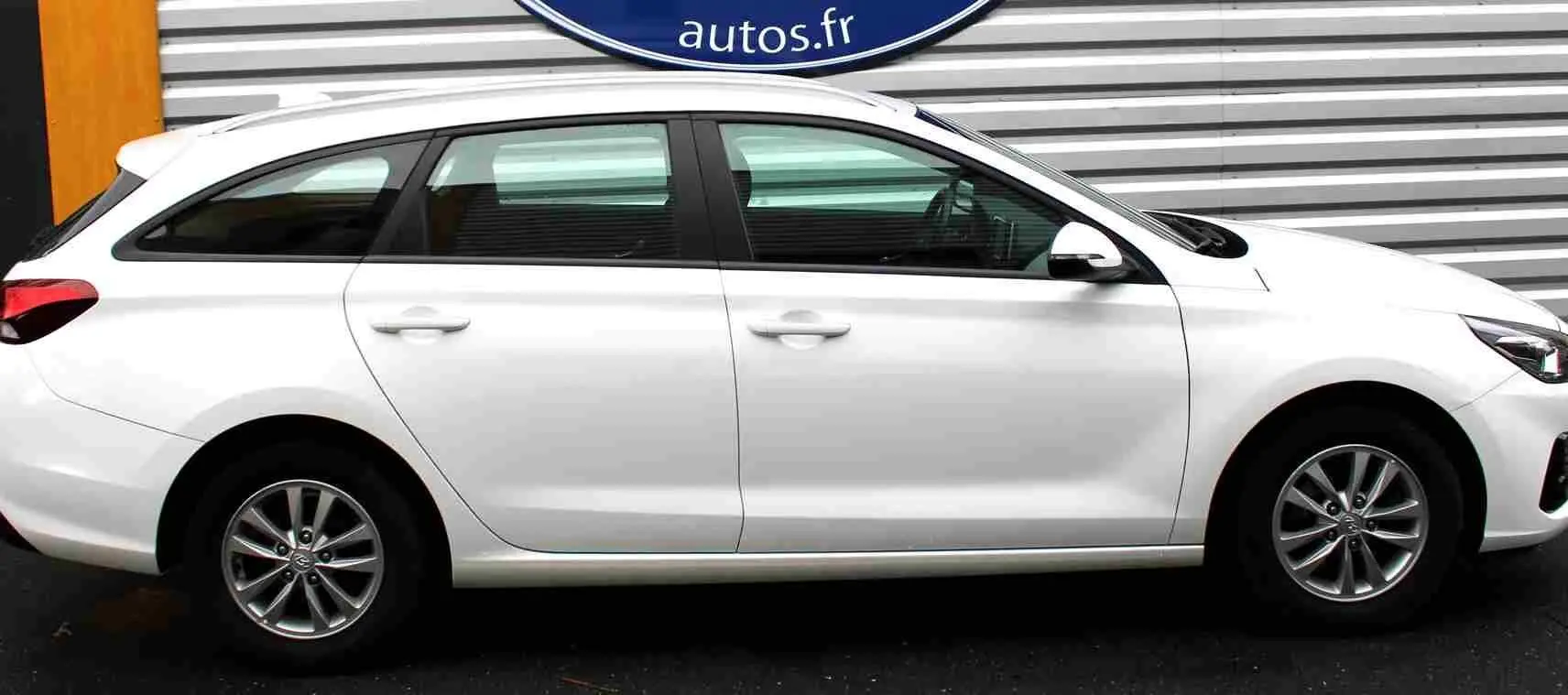 Profil côté droit d'une Hyundai i30 SW blanche polaire 2022 avec jantes alliage et vitres teintées.