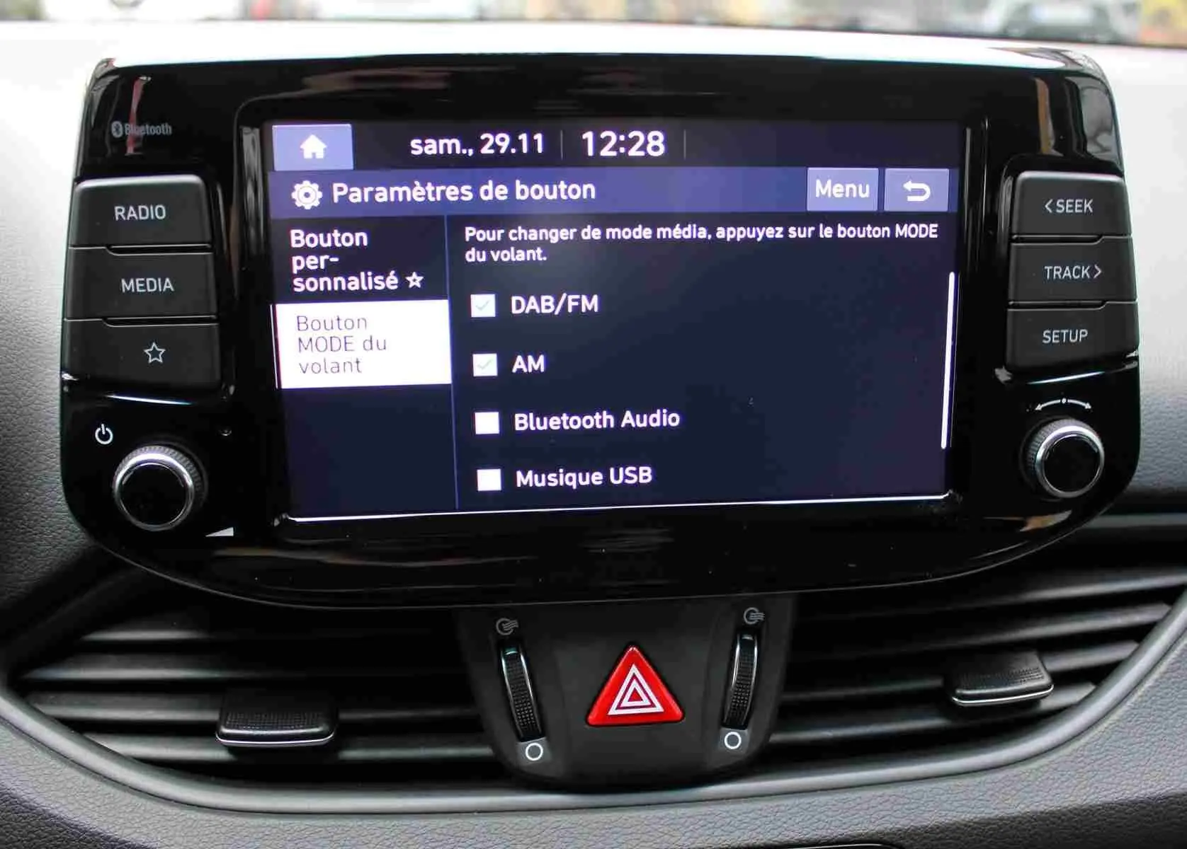 Écran tactile central de la Hyundai i30 SW blanc polaire 2022 affichant les options audio et boutons de commande.