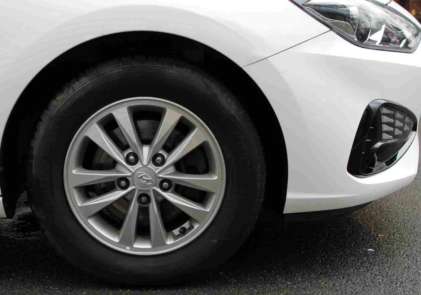 Gros plan sur la roue avant gauche et le pare-chocs blanc polaire d'une Hyundai i30 SW 2022 finition Comfort.