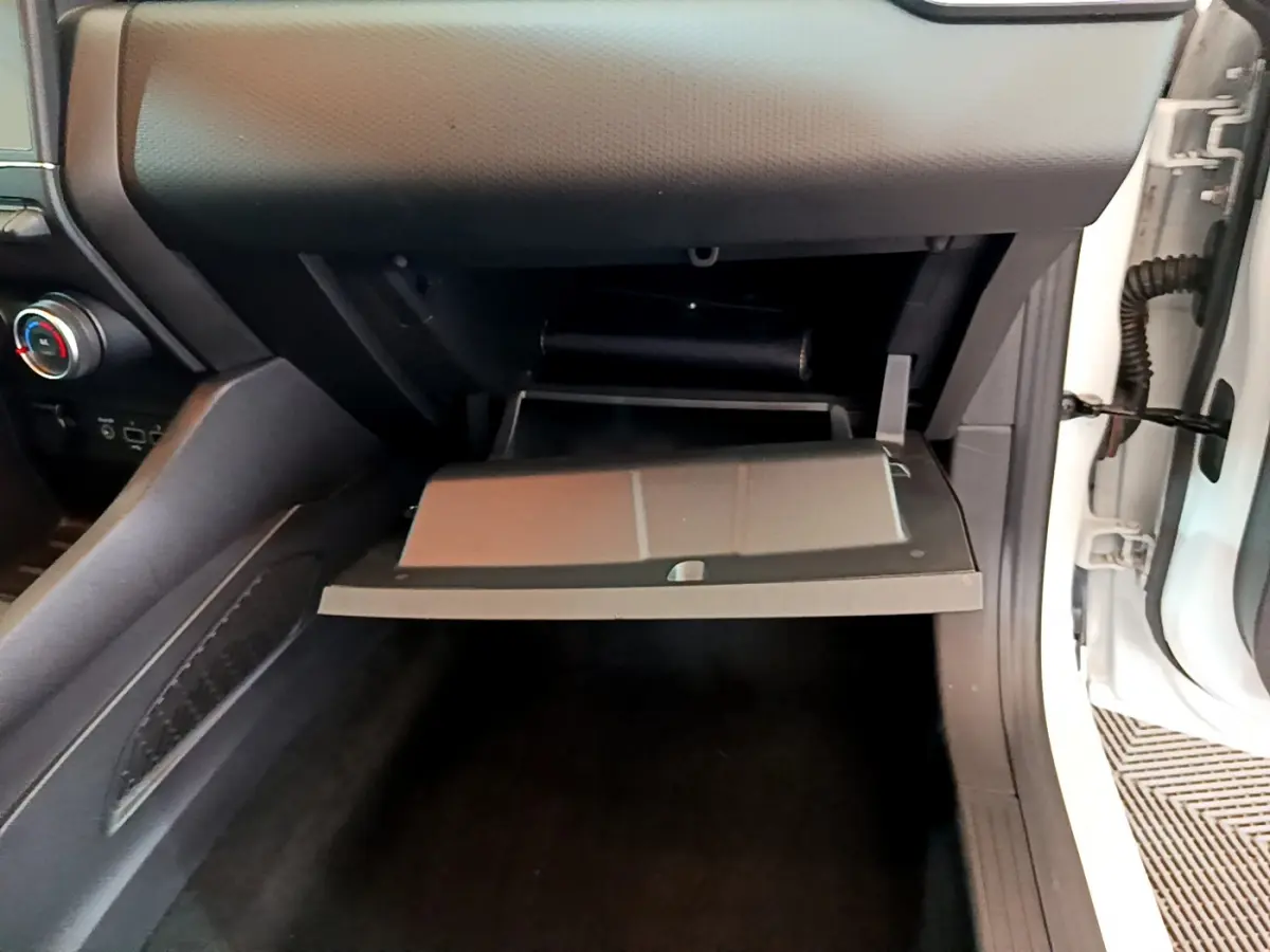 Vue rapprochée de la boîte à gants ouverte côté passager d'une Renault Clio Business blanche de 2020.