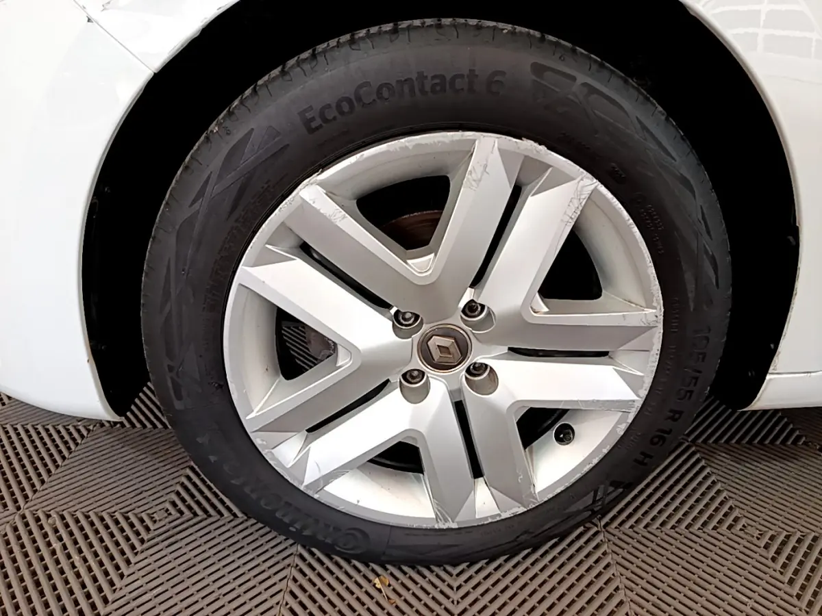 Gros plan sur la roue avant droite blanche d'une Renault Clio Business TCe 100 avec jante alliage griffée.