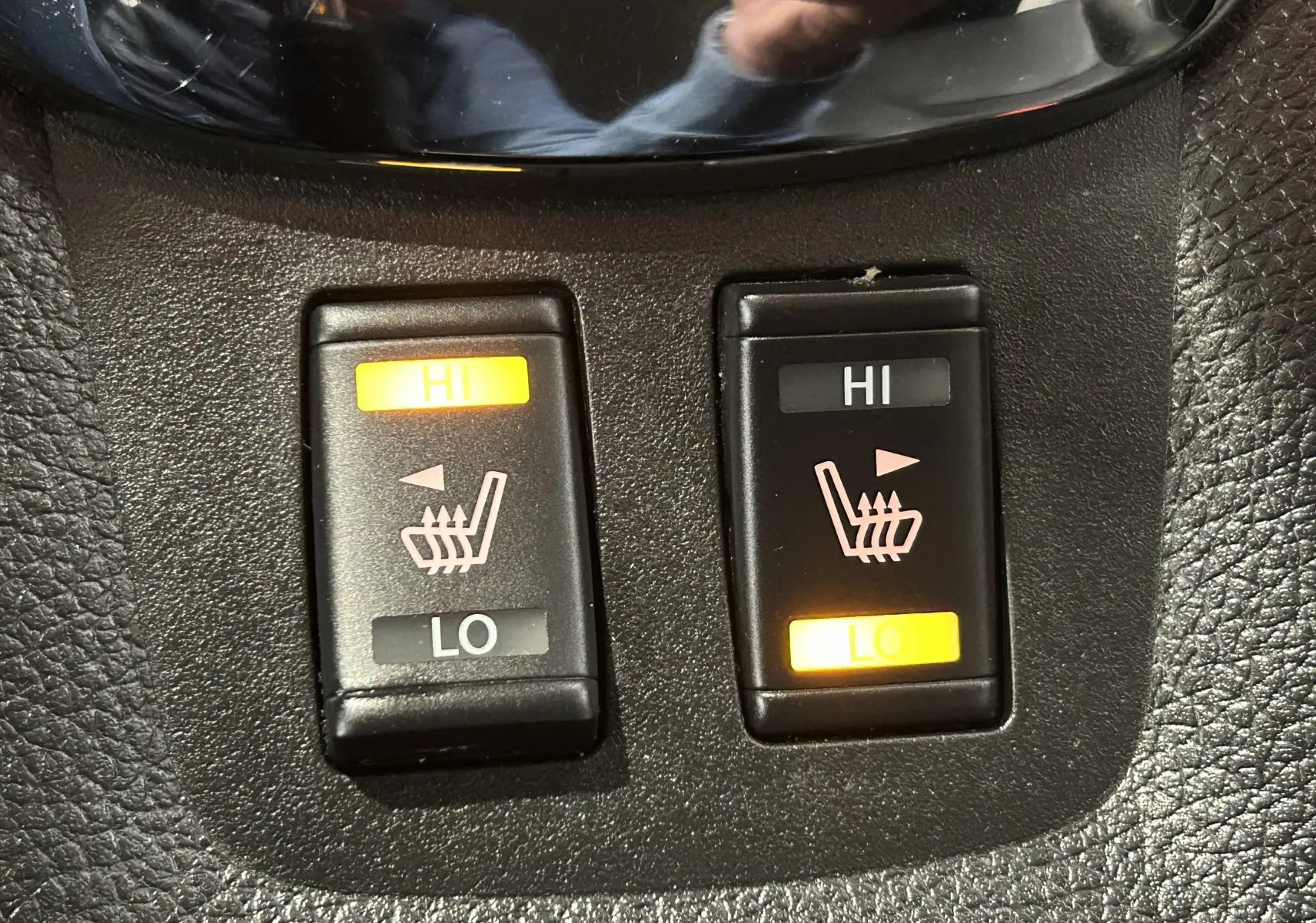 Gros plan sur les boutons de réglage des sièges chauffants, intérieur noir de la Nissan Pulsar gris 2018.