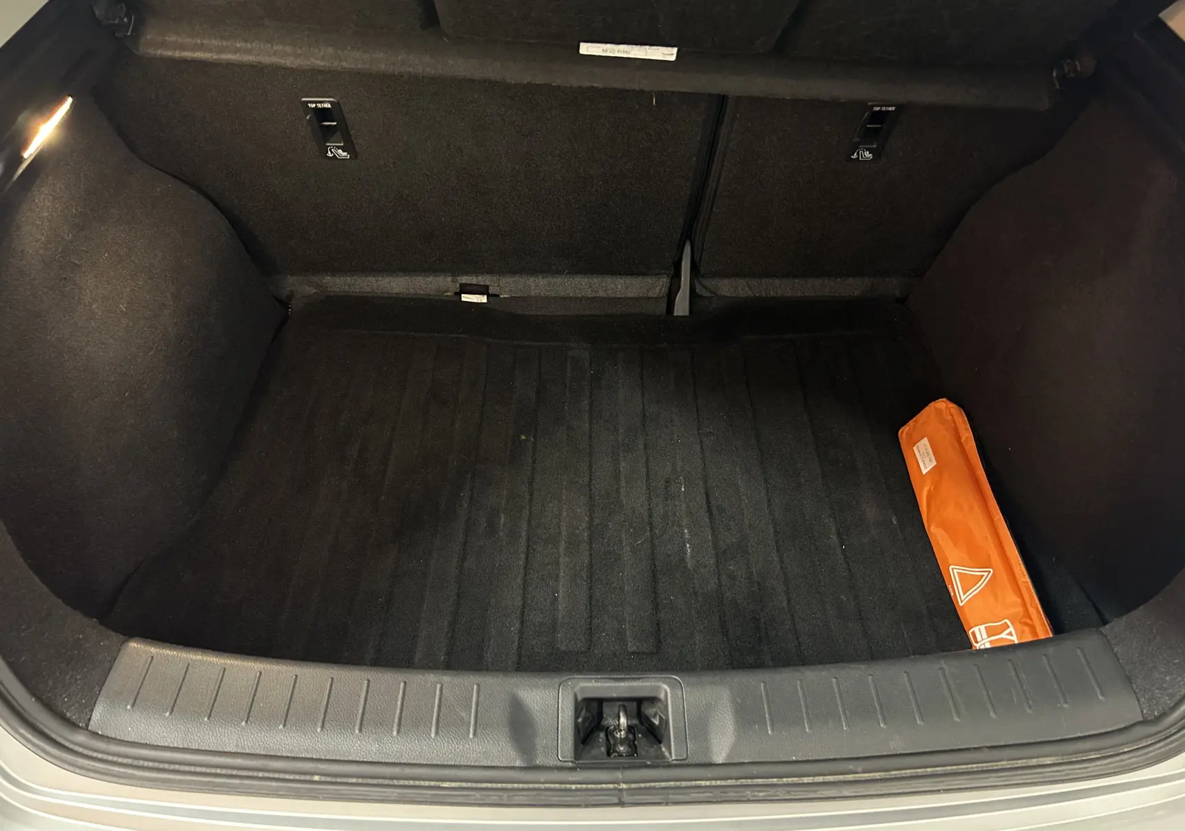 Coffre ouvert de la Nissan Pulsar gris, montrant un espace de rangement propre avec un triangle de signalisation orange sur la droite.