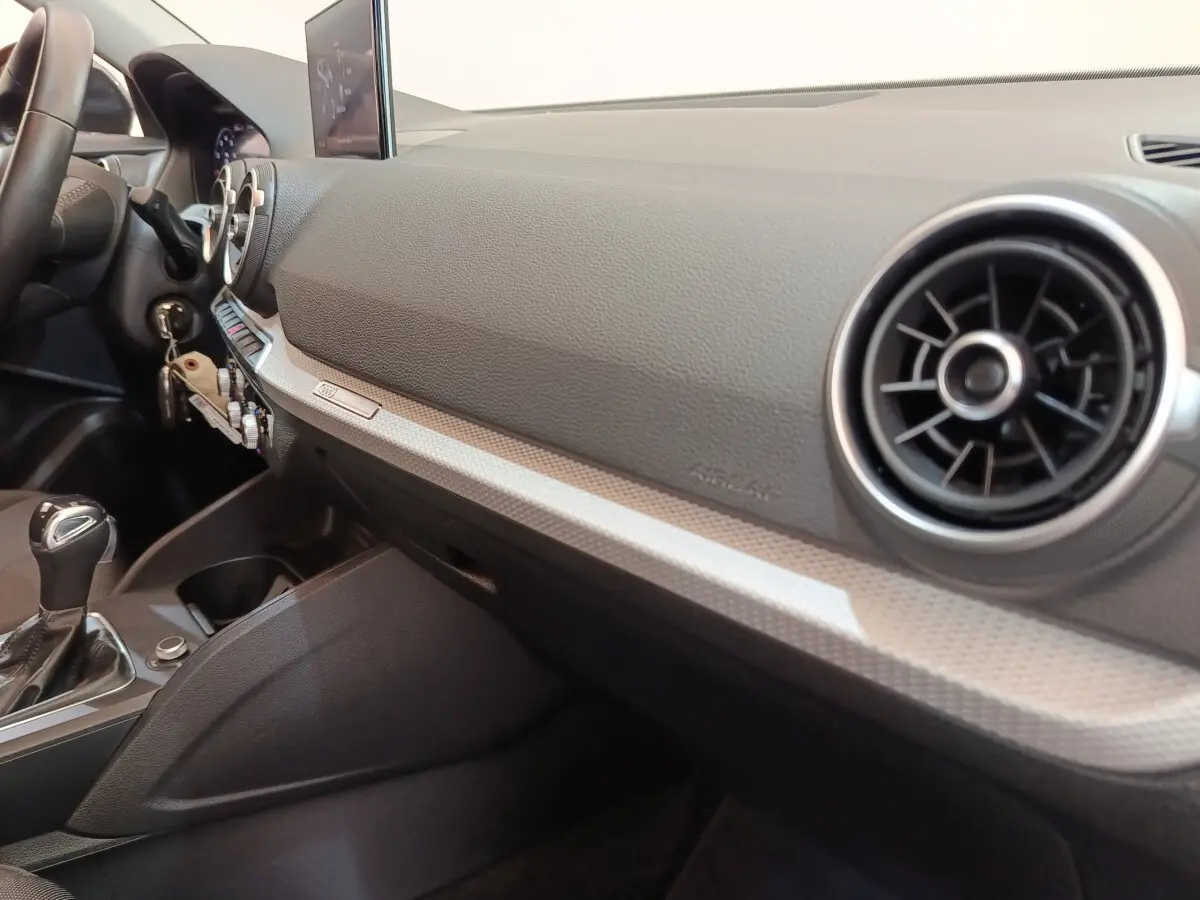 Vue intérieure côté passager de l’Audi Q2 35 TFSI 2022, tableau de bord gris foncé avec aérateurs ronds chromés.