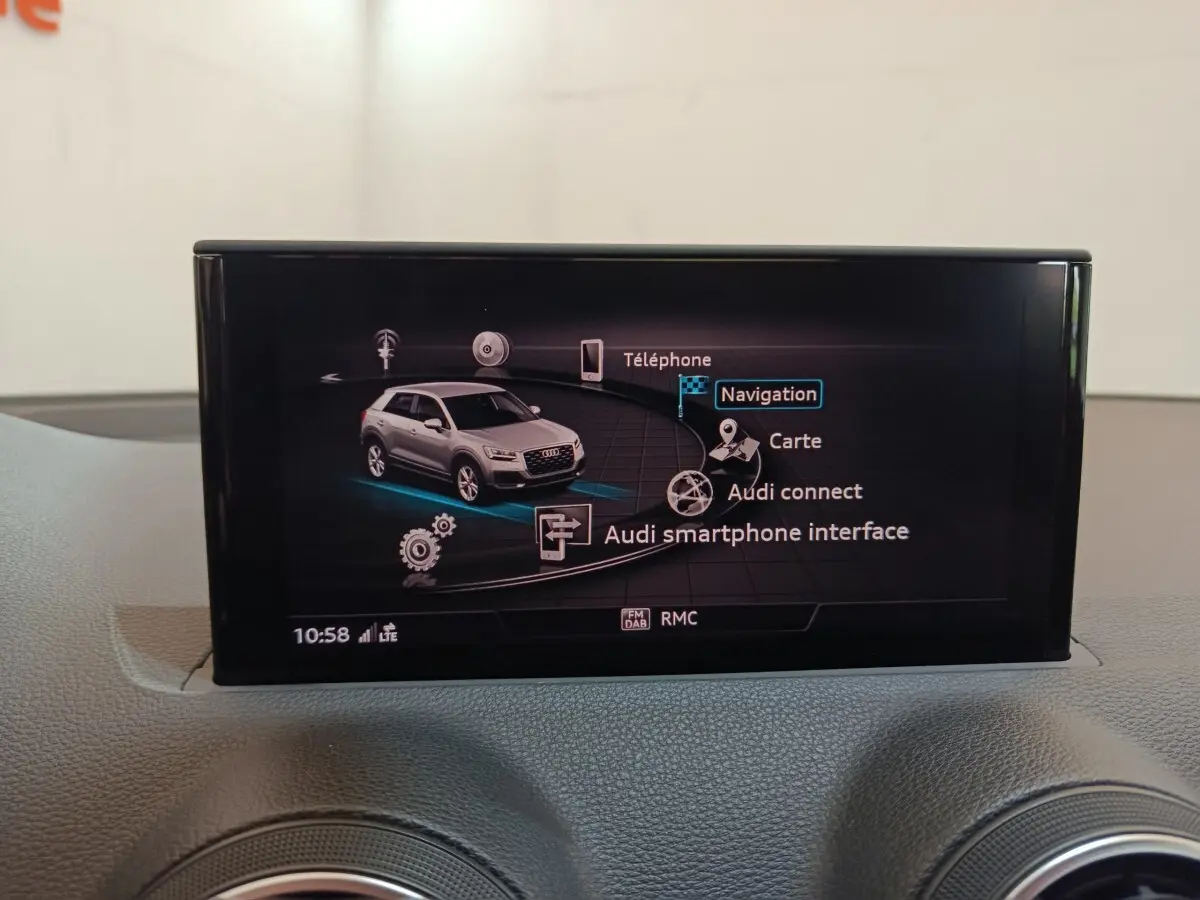 Écran tactile intérieur affichant le menu de navigation avec une image grise de l'Audi Q2 en vue 3/4 avant.