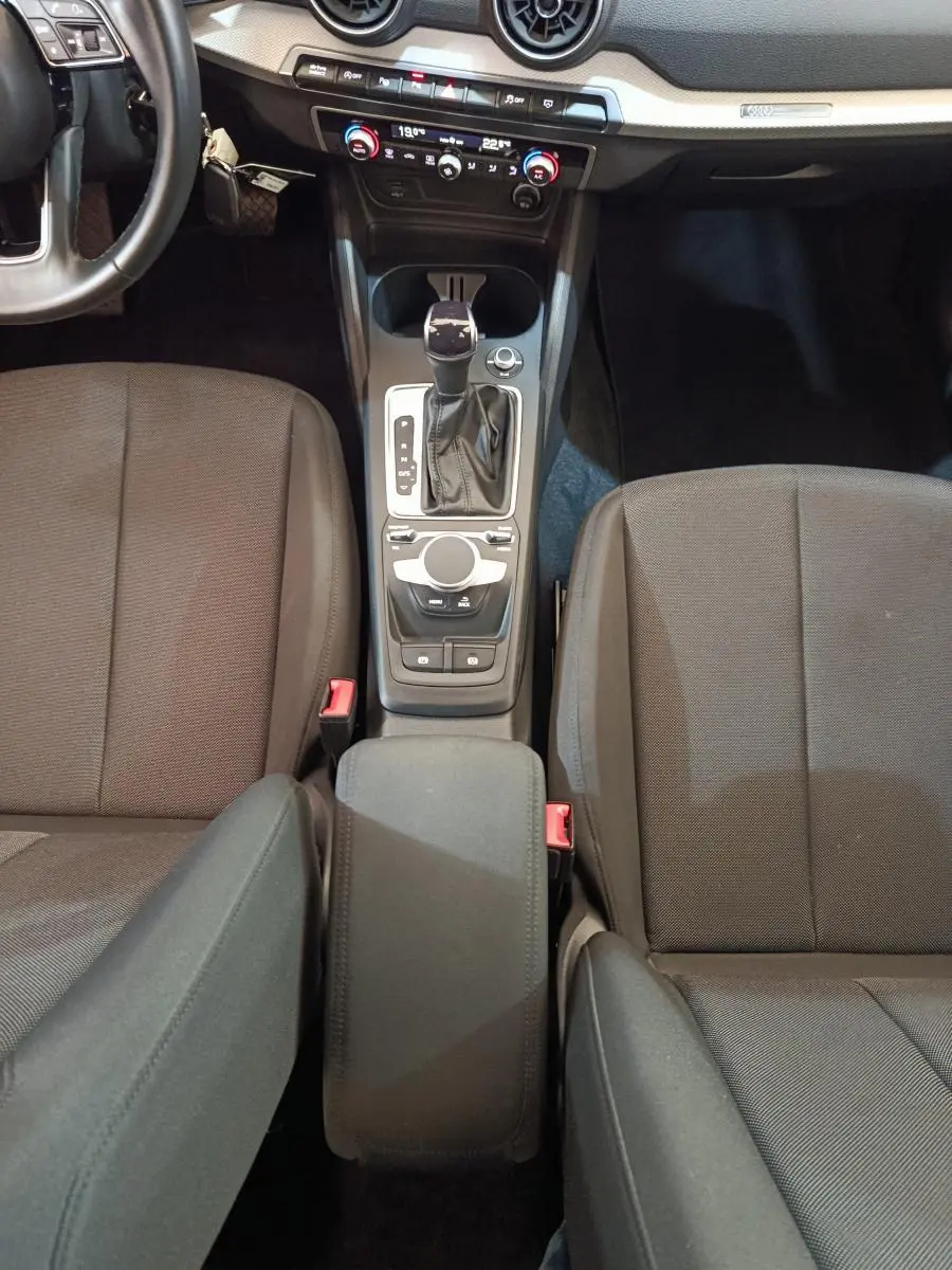 Vue intérieure centrée sur la console centrale et les sièges avant gris foncé de l'Audi Q2 35 TFSI 2022.
