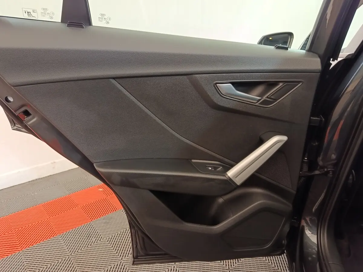 Vue intérieure de la porte arrière droite gris foncé de l'Audi Q2 35 TFSI 150 S Tronic Business Line avec poignée argentée.