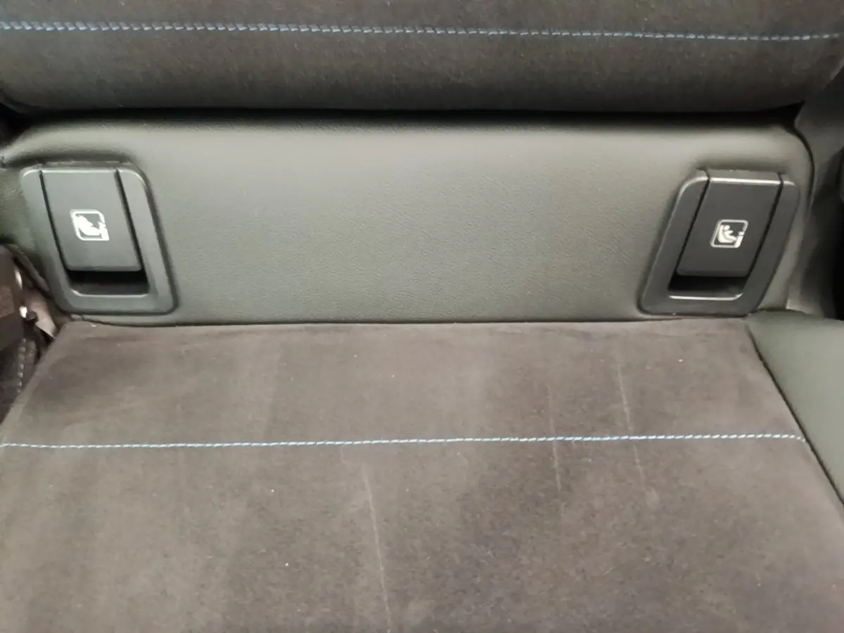 Détail de la banquette arrière en tissu gris foncé avec surpiqûres bleues et commandes de rabattement sur BMW X1 xDrive25e M Sport.