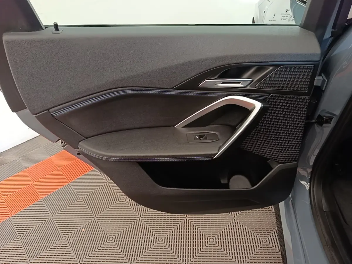 Vue rapprochée de la porte avant droite gris foncé du BMW X1 xDrive25e M Sport avec garniture noire et insert alu.