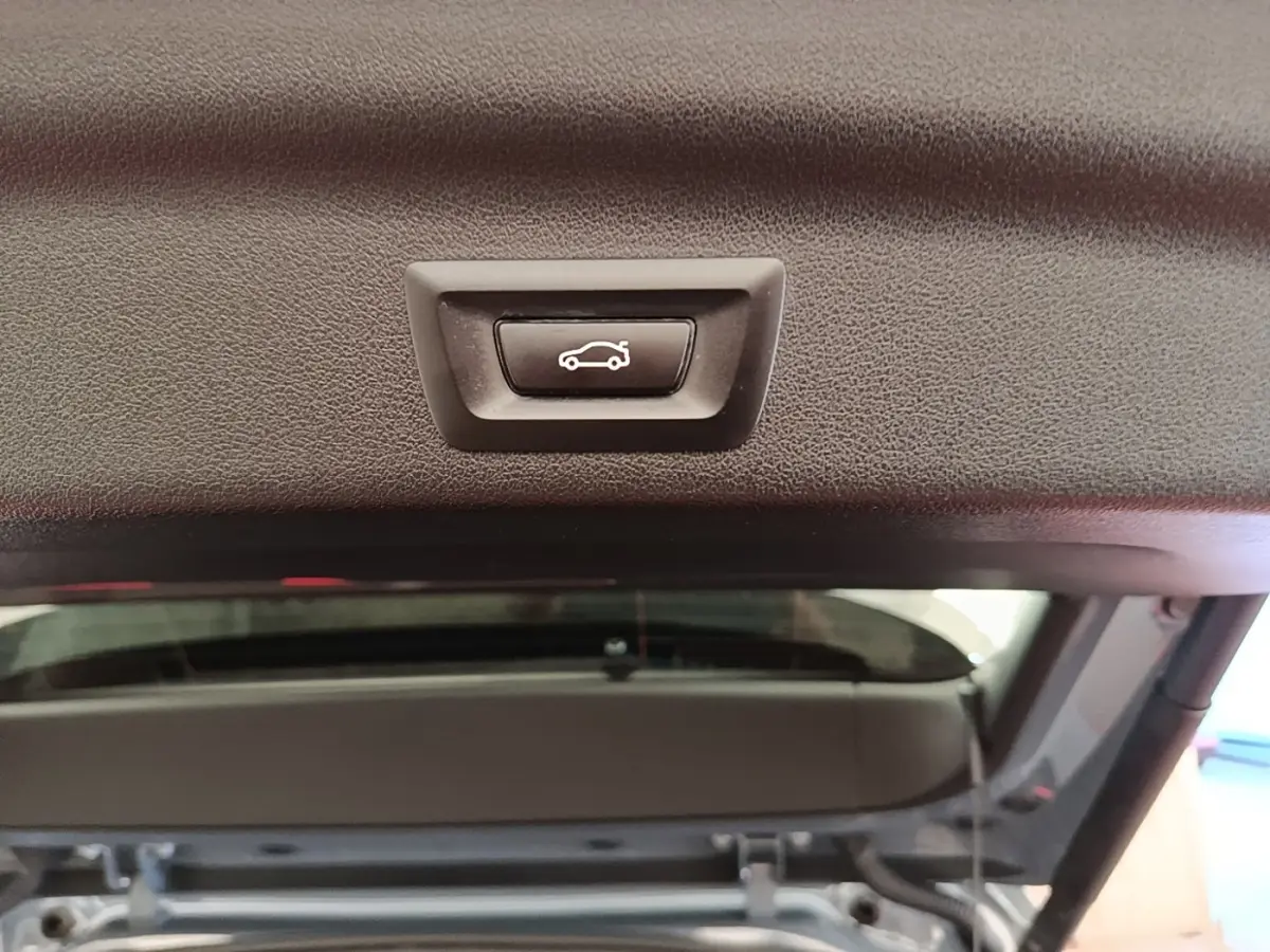 Bouton d'ouverture électrique du coffre sur la partie intérieure du hayon d'un BMW X1 gris foncé 2023.