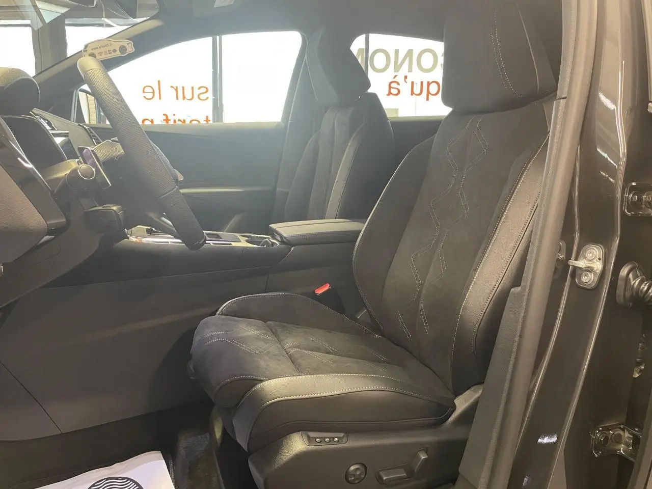 Vue intérieure côté conducteur du DS7 Crossback gris titanium, mettant en valeur les sièges en Alcantara noir profond avec surpiqûres.