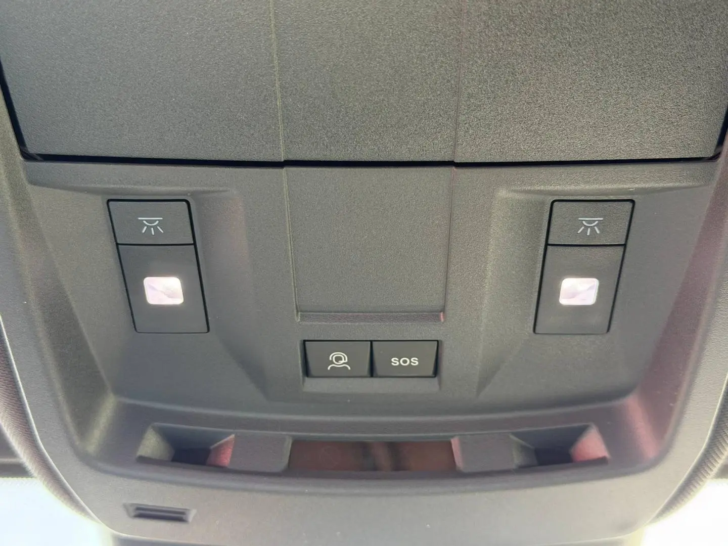 Gros plan sur la console de toit noire du Peugeot 3008 avec boutons d'éclairage et SOS visibles.