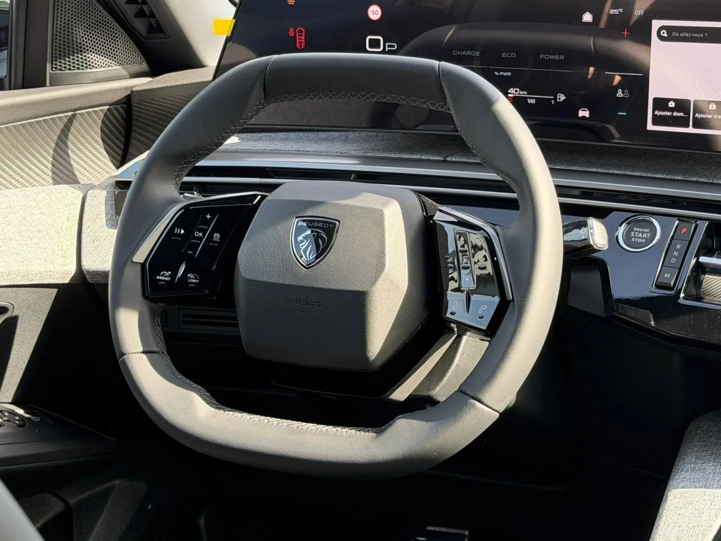 Vue rapprochée du volant cuir gris du Peugeot 3008 2026 avec commandes multifonctions et tableau de bord numérique.